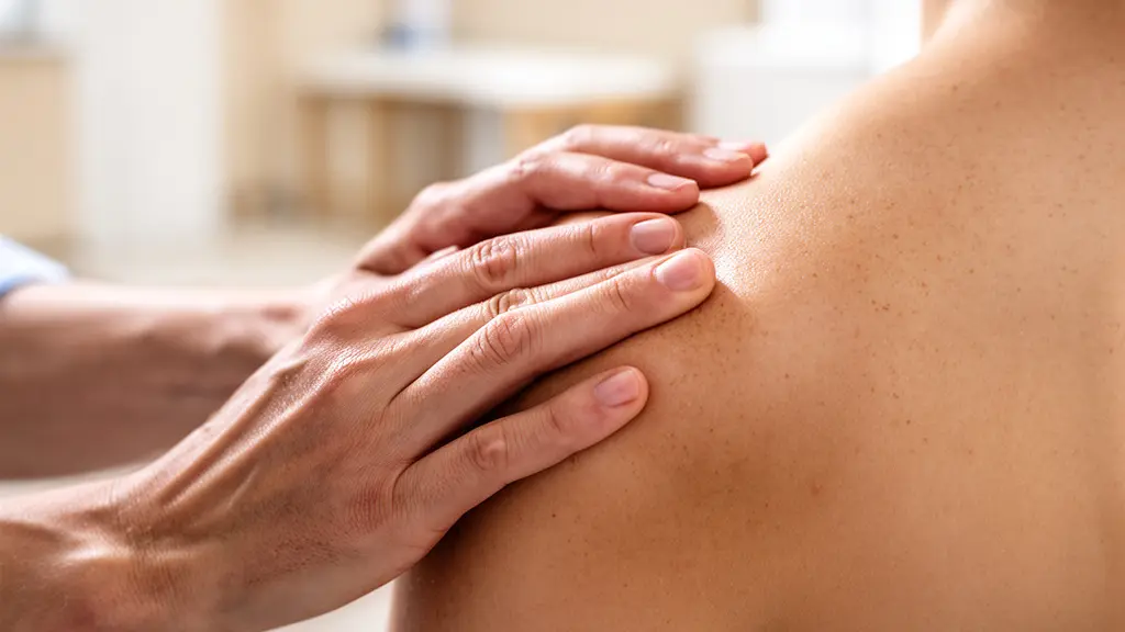 Vue macro de mains expertes pratiquant une manipulation thérapeutique sur une épaule, ambiance zen épurée