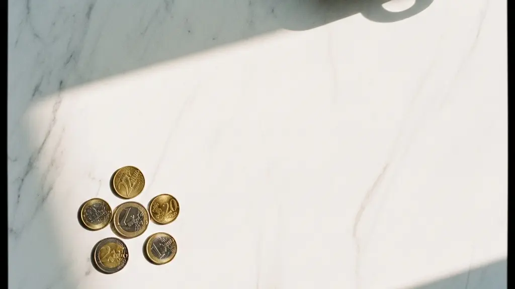 Vue plongeante minimaliste sur quelques pièces de monnaie posées sur une surface claire, illustrant le seuil financier en dessous duquel l'assurance refuse d'intervenir