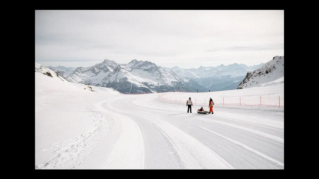 Scène large en montagne française avec une piste enneigée et une équipe de secours au loin, suggérant le coût potentiel des secours sur domaine skiable.