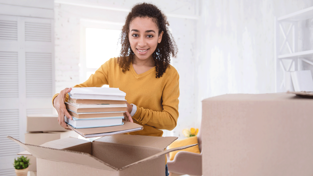 Jeune adulte dans un studio étudiant préparant ses affaires, symbolisant l'indépendance et la responsabilité